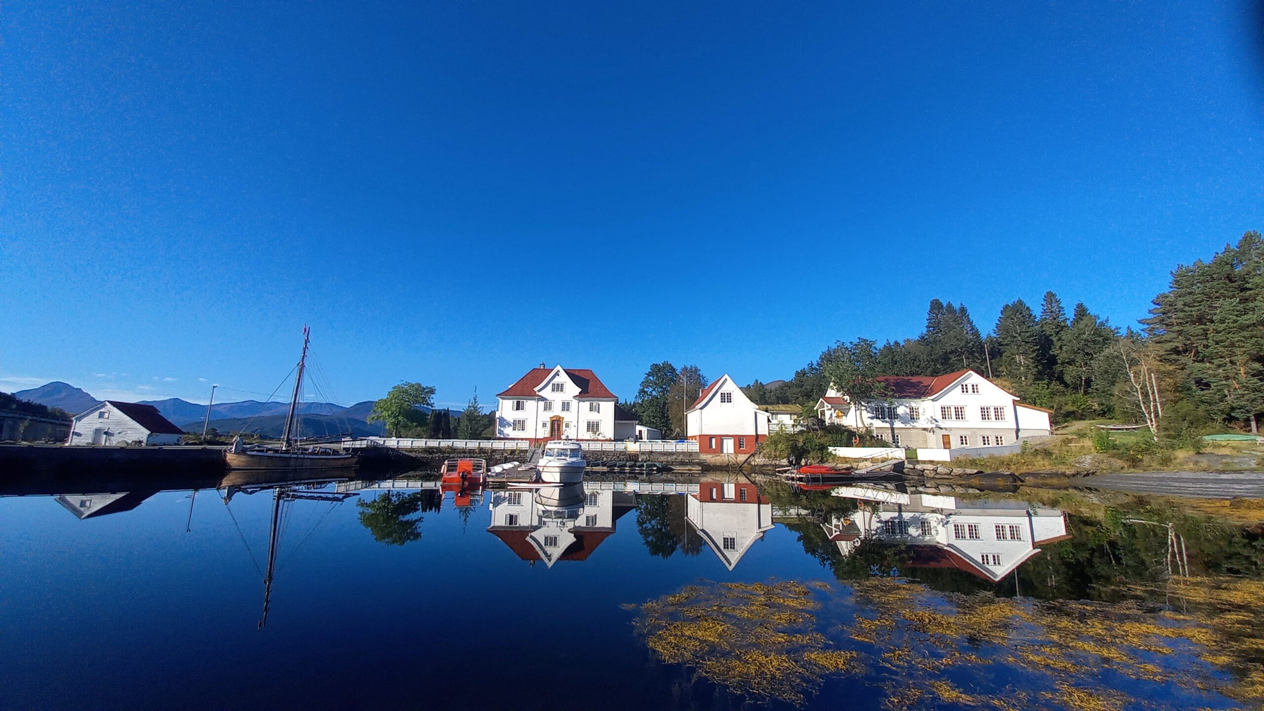 hovedbygninger på kjeldsund speiler seg i sjøen
